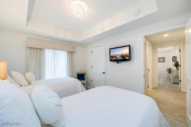 tiled bedroom with a tray ceiling