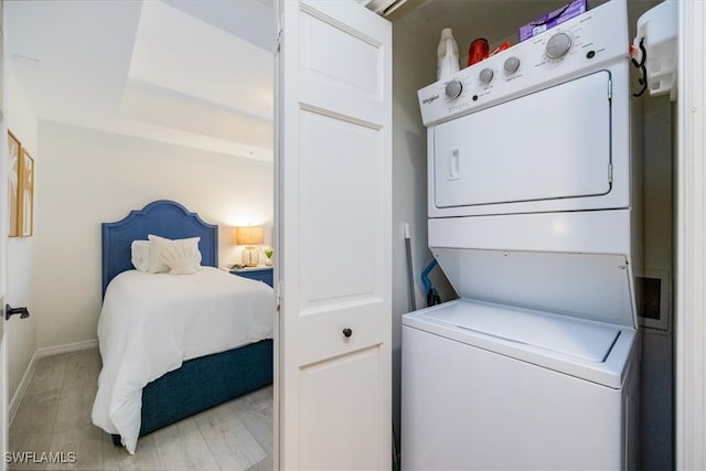 clothes washing area featuring light hardwood / wood-style flooring and stacked washer / drying machine