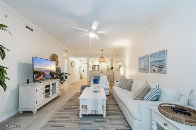 living room featuring light hardwood / wood-style floors, ceiling fan, and crown molding