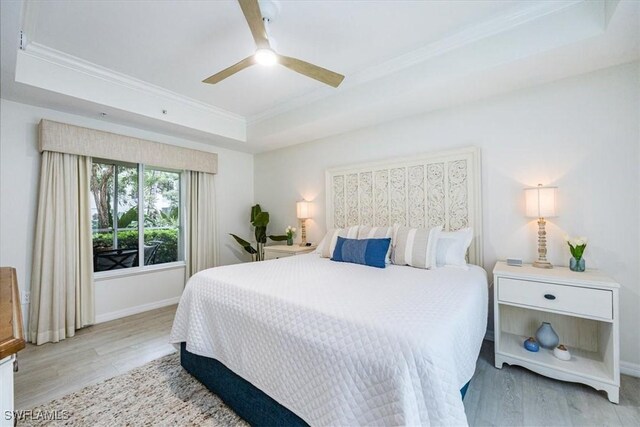 bedroom with ceiling fan, a raised ceiling, and light hardwood / wood-style flooring