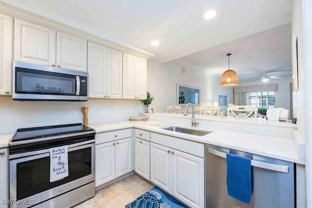 kitchen with sink, kitchen peninsula, appliances with stainless steel finishes, light tile patterned floors, and crown molding