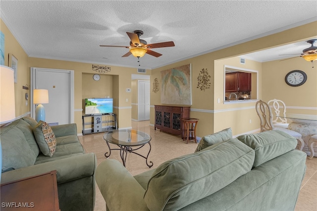 living room with ceiling fan, a textured ceiling, light tile patterned floors, and ornamental molding