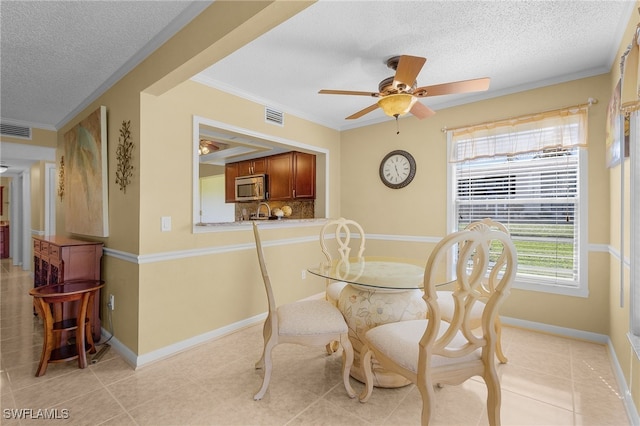 tiled dining area featuring ceiling fan, a textured ceiling, and crown molding