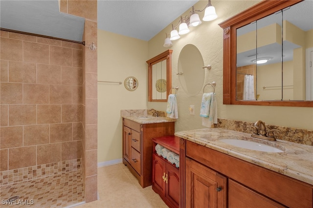 bathroom featuring tile patterned floors, vanity, a textured ceiling, and a tile shower