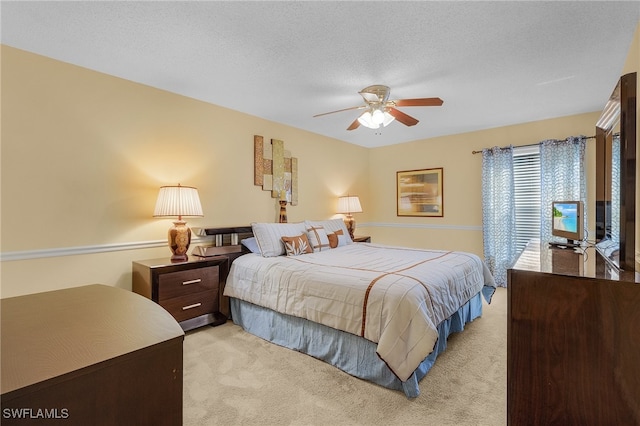 bedroom featuring a textured ceiling, light carpet, and ceiling fan