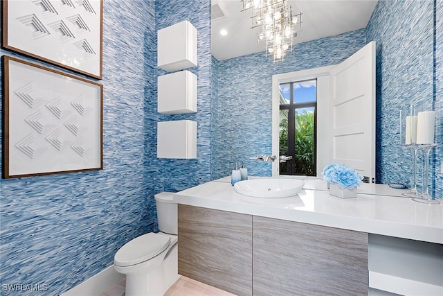 bathroom featuring a notable chandelier, toilet, and vanity