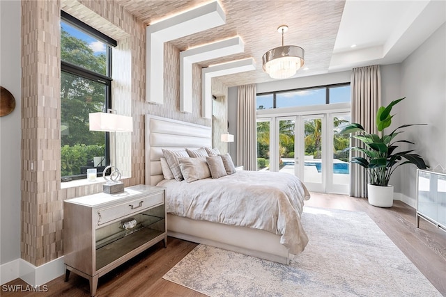 bedroom with access to exterior, french doors, multiple windows, and wood-type flooring