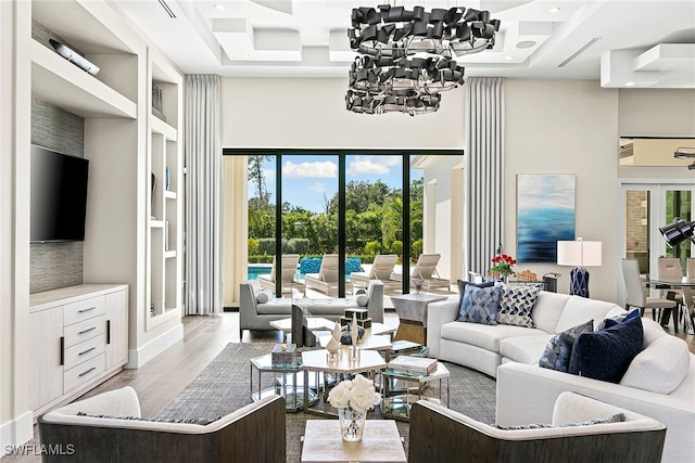 living room featuring a chandelier, a healthy amount of sunlight, a tray ceiling, and light hardwood / wood-style flooring