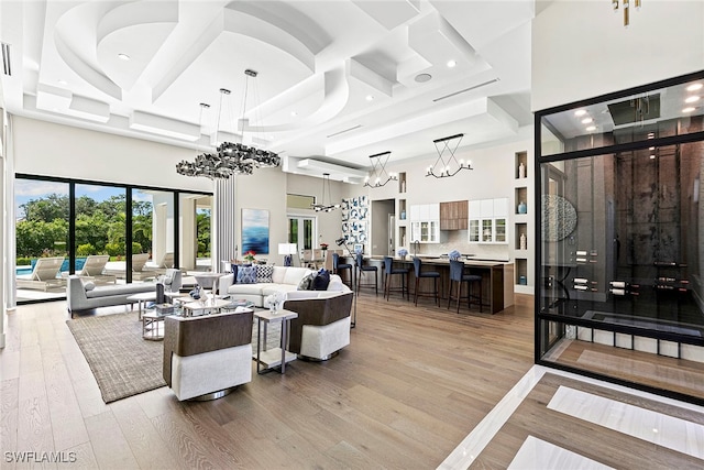 living room with a high ceiling, light wood-type flooring, and an inviting chandelier