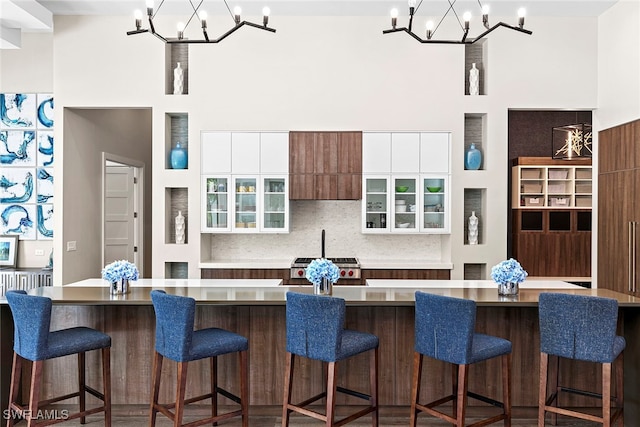 kitchen with a kitchen bar, white cabinetry, a spacious island, and an inviting chandelier