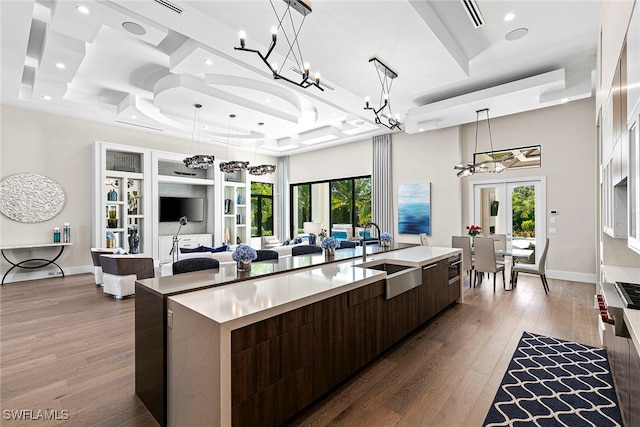 kitchen featuring dark brown cabinetry, a large island, sink, and a healthy amount of sunlight