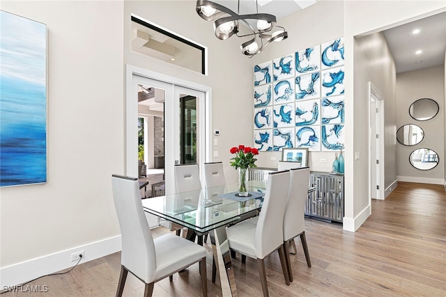 dining space with light hardwood / wood-style floors and a notable chandelier