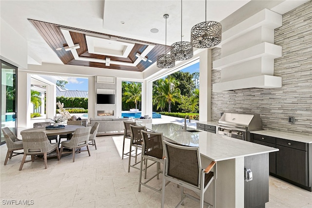 view of patio with grilling area, a wet bar, a fireplace, and an outdoor kitchen