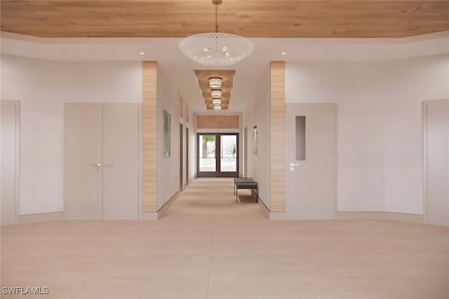 corridor featuring french doors, wooden ceiling, a high ceiling, a notable chandelier, and light tile patterned floors