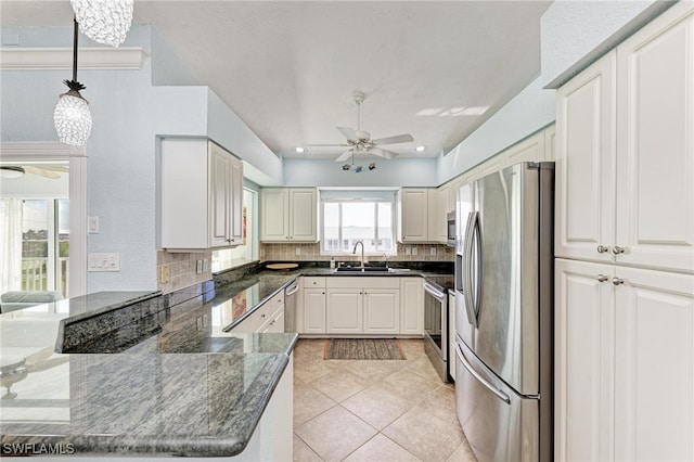 kitchen with kitchen peninsula, backsplash, appliances with stainless steel finishes, pendant lighting, and sink