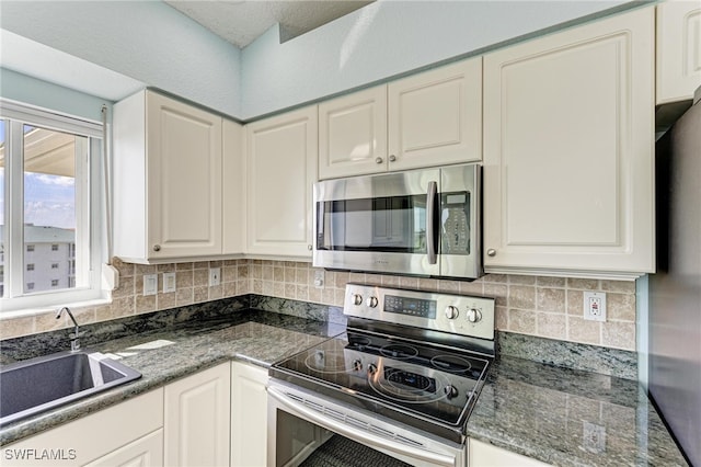 kitchen with white cabinetry, stainless steel appliances, sink, and backsplash