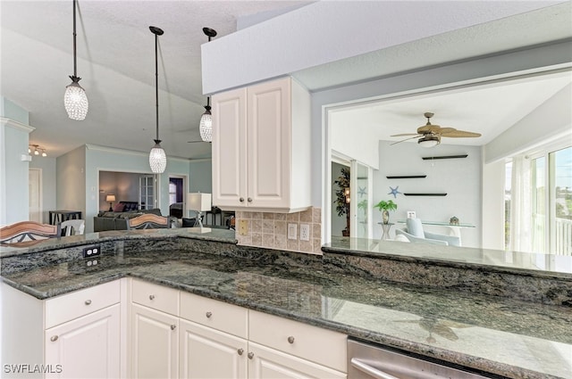 kitchen featuring lofted ceiling, backsplash, dark stone countertops, pendant lighting, and white cabinetry