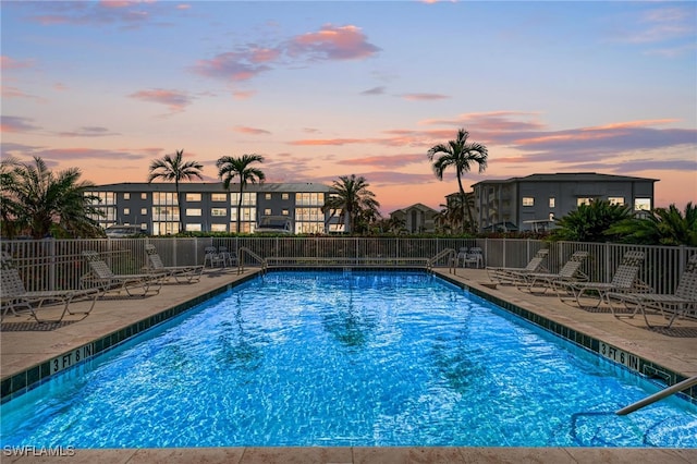 pool at dusk with a patio area