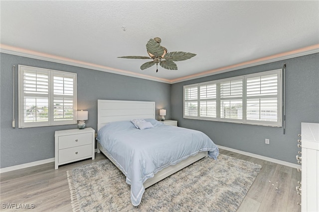 bedroom with ceiling fan, hardwood / wood-style flooring, a textured ceiling, and crown molding