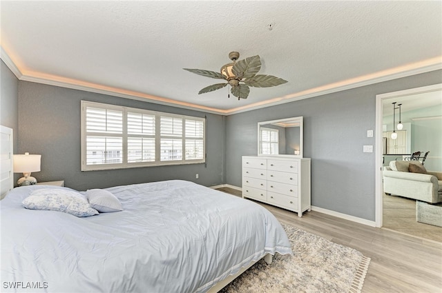 bedroom with ornamental molding, light hardwood / wood-style flooring, a textured ceiling, and ceiling fan