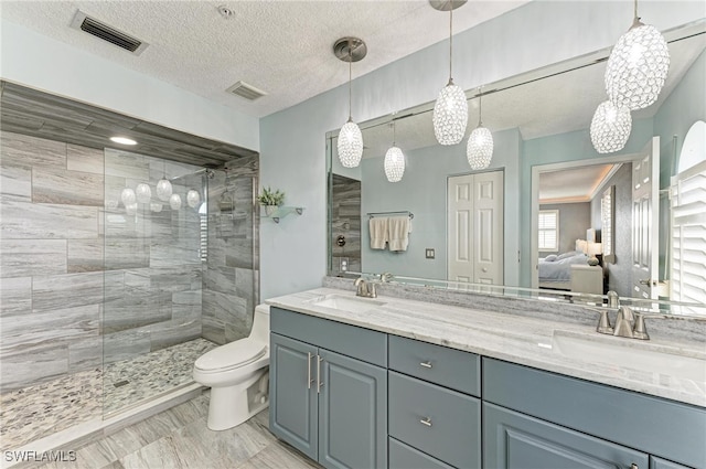 bathroom featuring vanity, toilet, a textured ceiling, and a tile shower