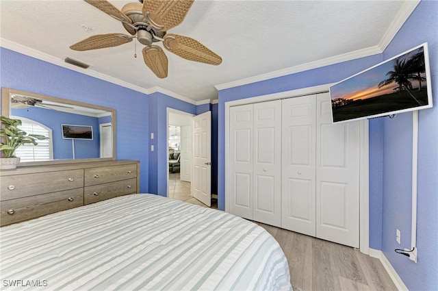 bedroom with a textured ceiling, a closet, ceiling fan, ornamental molding, and light hardwood / wood-style flooring