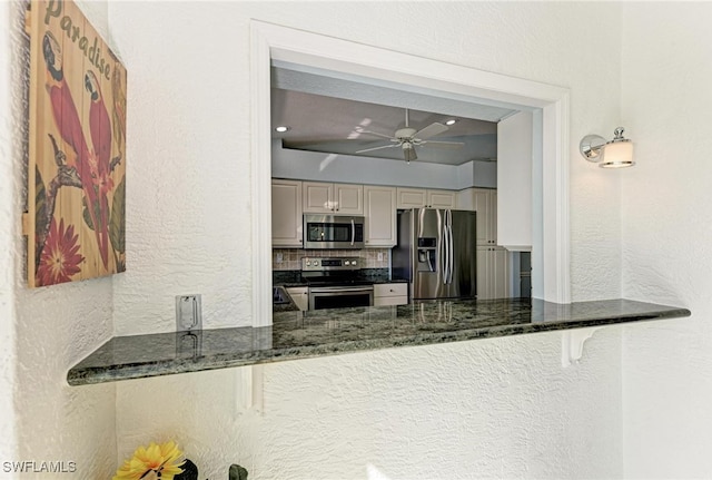 kitchen with appliances with stainless steel finishes, dark stone countertops, tasteful backsplash, and ceiling fan