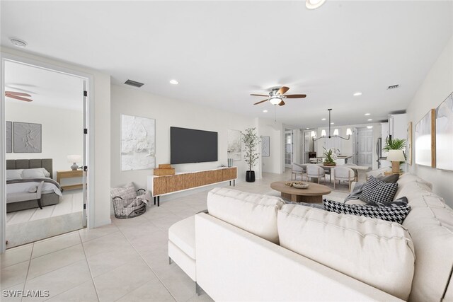 living room featuring light tile patterned flooring and ceiling fan with notable chandelier