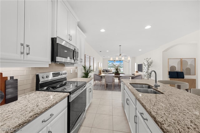 kitchen with light stone countertops, appliances with stainless steel finishes, sink, light tile patterned floors, and white cabinetry