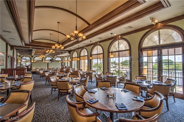 dining space with a raised ceiling, ornamental molding, a wealth of natural light, and an inviting chandelier