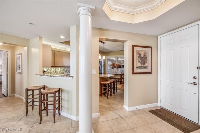 tiled foyer with crown molding and decorative columns