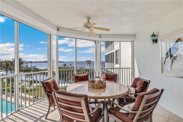 sunroom featuring plenty of natural light, ceiling fan, and a water view