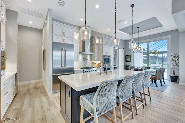 kitchen featuring light wood-type flooring, white cabinetry, stainless steel appliances, and a kitchen island with sink