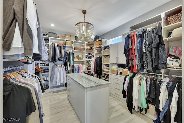 spacious closet with light wood-type flooring and a notable chandelier