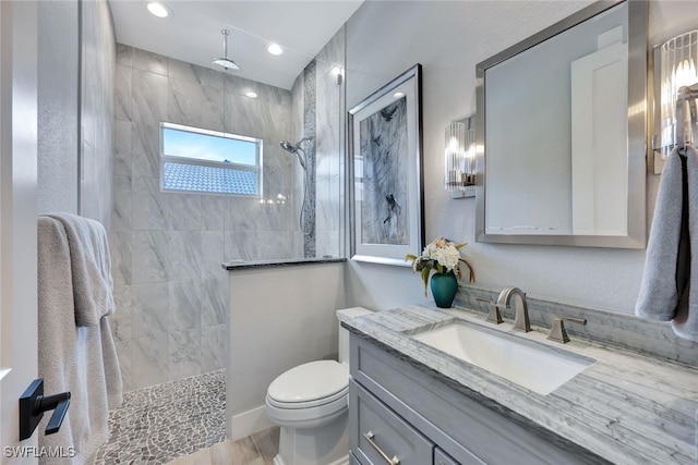 bathroom with vanity, toilet, wood-type flooring, and tiled shower