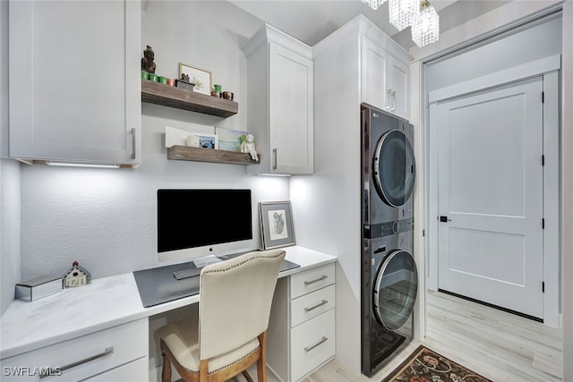 home office featuring built in desk, stacked washing maching and dryer, and light hardwood / wood-style flooring