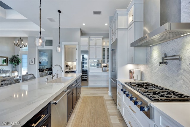 kitchen featuring white cabinets, decorative light fixtures, and wall chimney exhaust hood