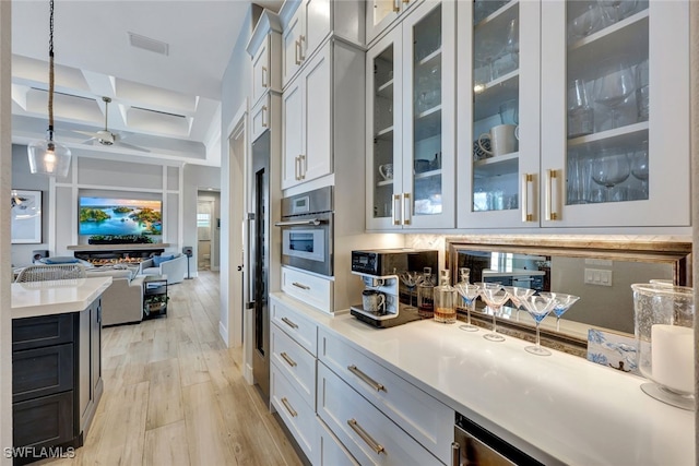 kitchen featuring appliances with stainless steel finishes, coffered ceiling, light hardwood / wood-style flooring, white cabinetry, and hanging light fixtures