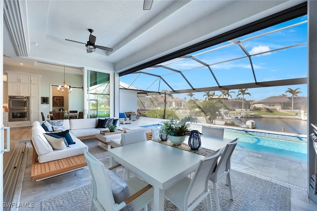 view of patio with ceiling fan, a water view, an outdoor hangout area, and glass enclosure