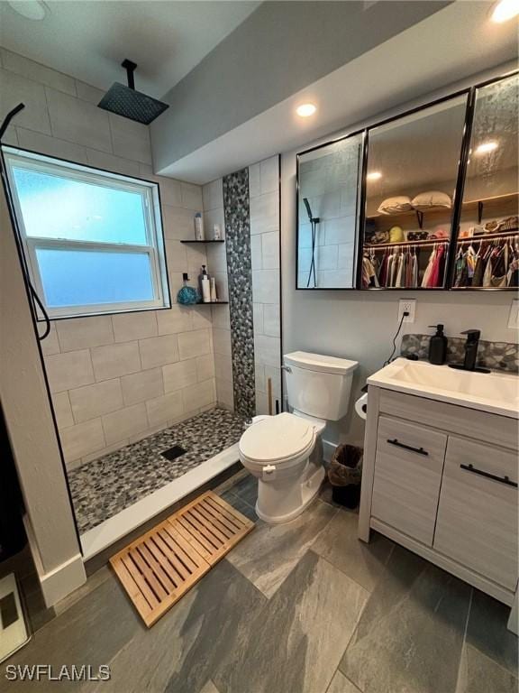 bathroom with vanity, toilet, and tiled shower