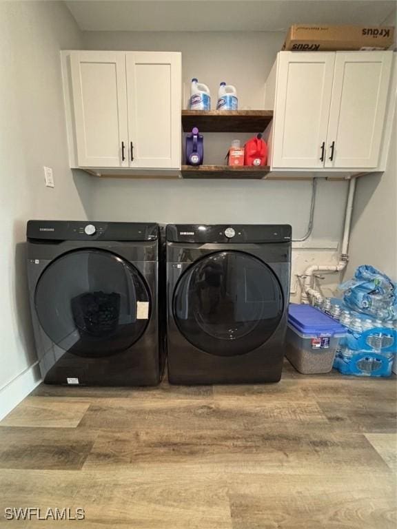 laundry room featuring cabinets, washer and clothes dryer, and light hardwood / wood-style flooring