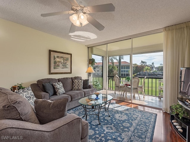 living room with a wall of windows, a textured ceiling, wood-type flooring, and ceiling fan