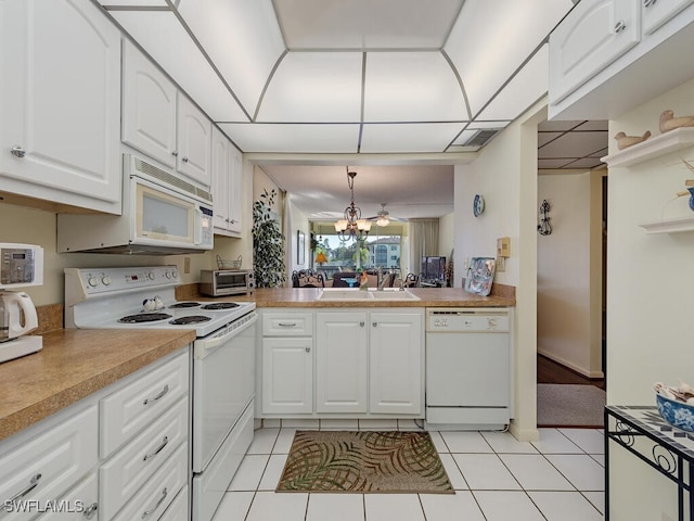 kitchen with white appliances, hanging light fixtures, light tile patterned flooring, and white cabinets