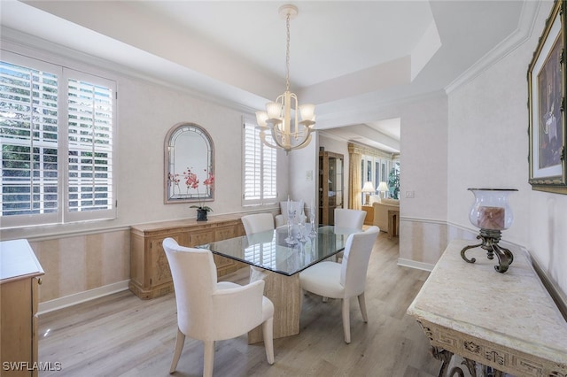 dining room with a chandelier, a raised ceiling, crown molding, and light hardwood / wood-style flooring