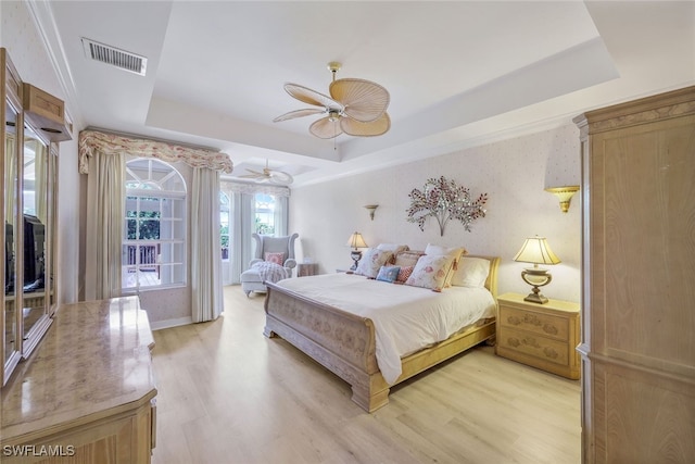 bedroom with ceiling fan, a raised ceiling, and light hardwood / wood-style flooring