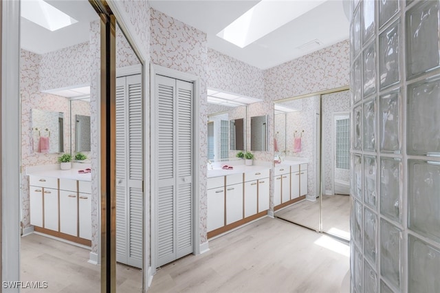 bathroom with hardwood / wood-style floors, vanity, and a skylight