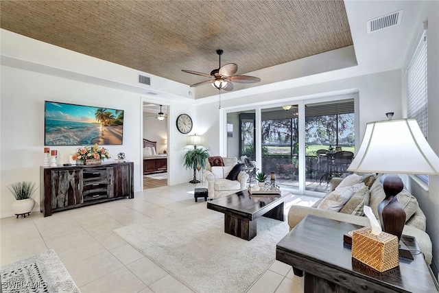 living room with ceiling fan, light tile patterned flooring, and a raised ceiling