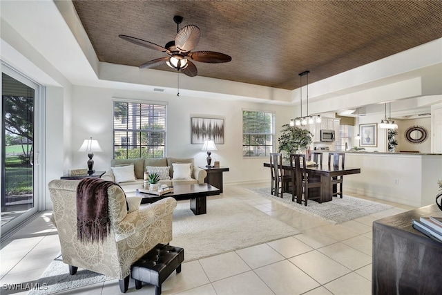 tiled living room featuring ceiling fan and a raised ceiling