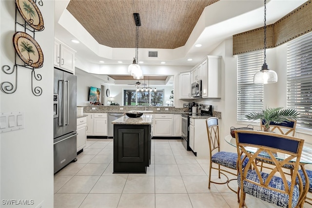 kitchen with stainless steel appliances, white cabinetry, pendant lighting, a tray ceiling, and a center island