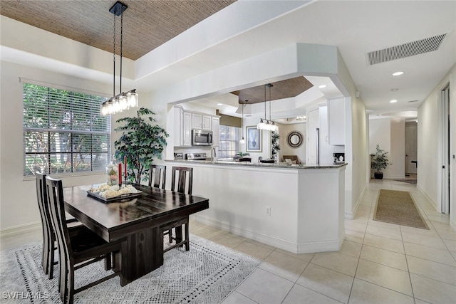 dining space featuring plenty of natural light, light tile patterned floors, and a tray ceiling